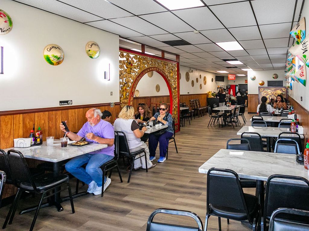 Dining room at Pho Dee-Licious with marble tables and a wall of painted conical hats