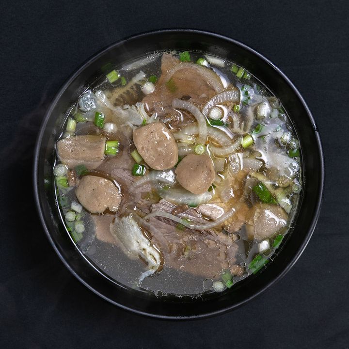 Steaming bowl of pho tai bo vien with rare steak and meatballs