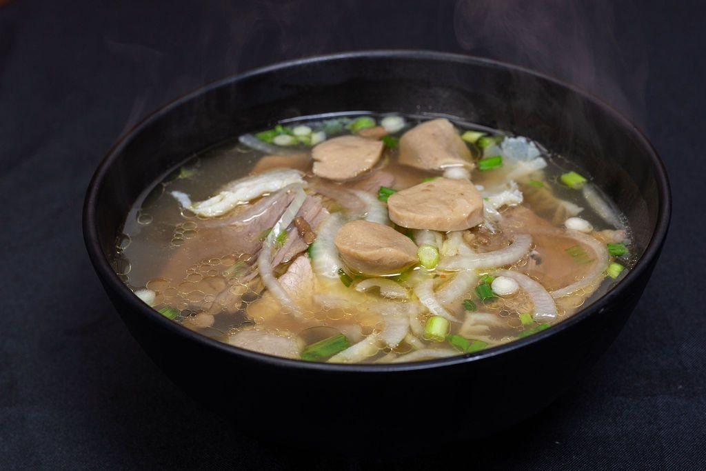 A steaming bowl of pho tai bo vien with rare steak and beef meatballs